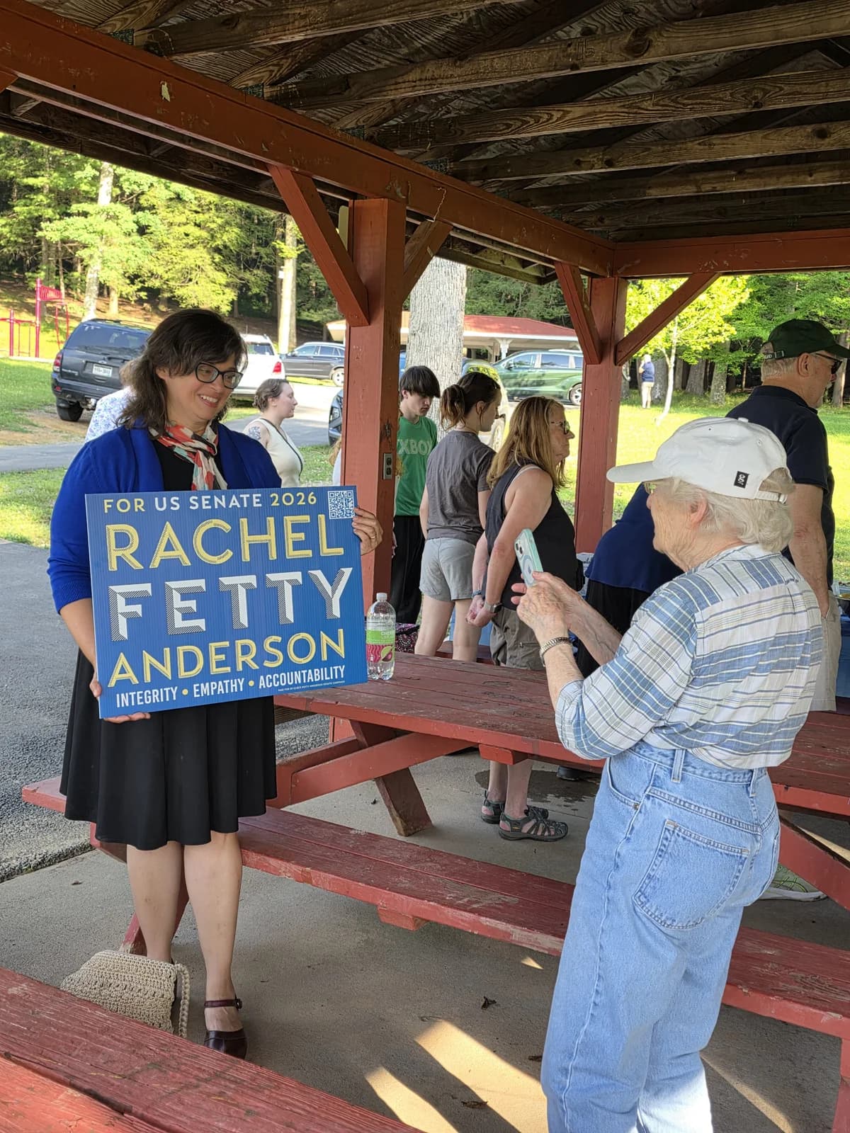 Rachel Fetty Anderson stands beside a campaign sign with volunteers.